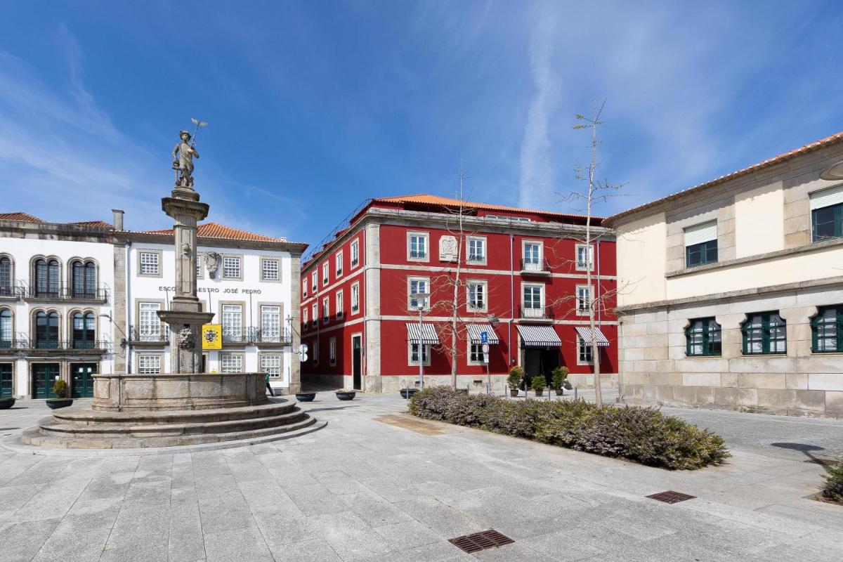 uma estátua em um pátio em frente a um prédio vermelho em AP Dona Aninhas em Viana do Castelo uma estátua em um pátio em frente a um prédio vermelho em AP Dona Aninhas em Viana do Castelo