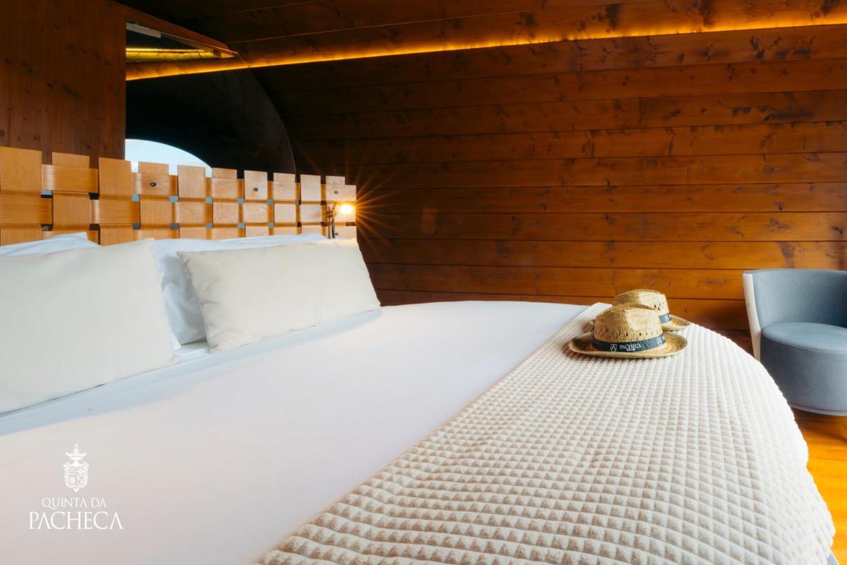 uma cama branca com um chapéu em cima dela em Pacheca The Wine House Hotel e Spa - Quinta da Pacheca em Lamego
