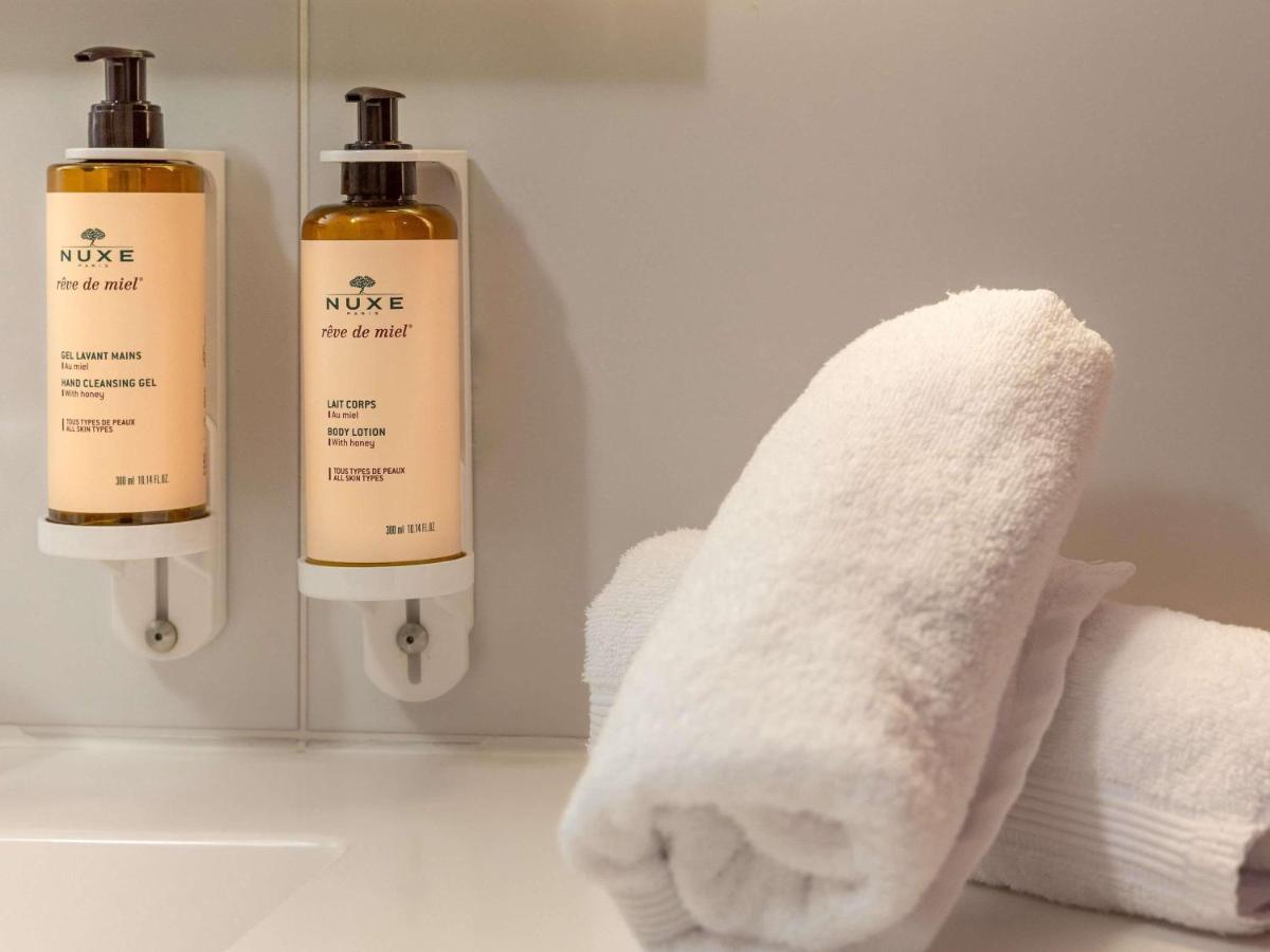 une salle de bain avec deux flacons de savon et des serviettes dans l'établissement Mercure Saint-Lary, à Saint-Lary-Soulan