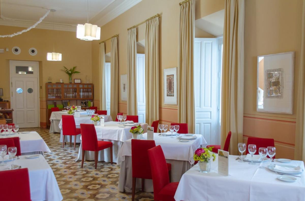 Un comedor con mesas blancas y sillas rojas. en Hotel Mirador de Llerena, en Llerena