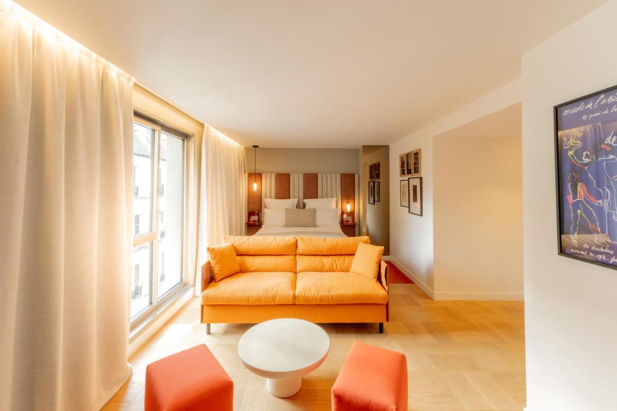 un salon avec un canapé orange et un lit dans l'établissement Hôtel Pilgrim, à Paris