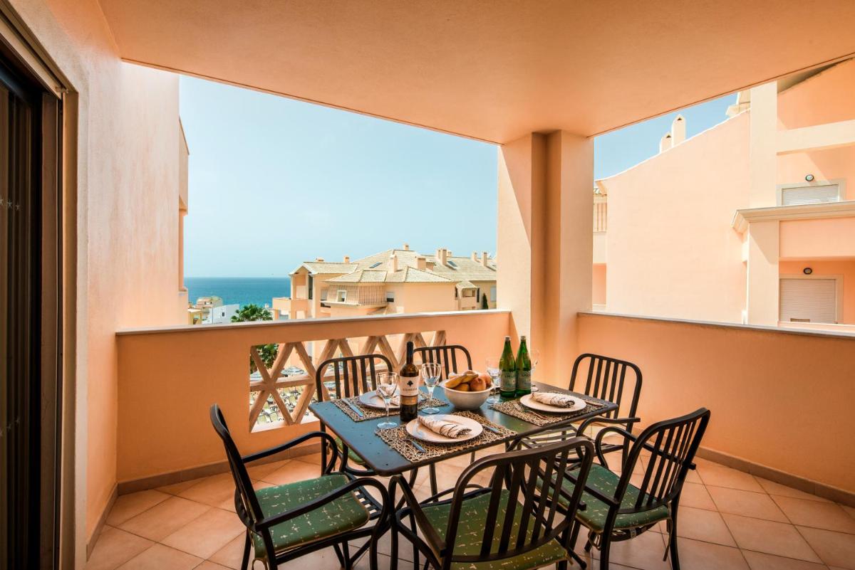 uma mesa e cadeiras numa varanda com vista para o oceano em Estrela da Luz Resort na Praia da Luz