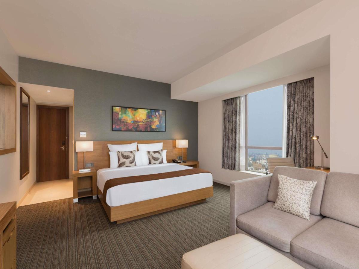 a large hotel room with a bed and a couch at Novotel Lucknow Gomti Nagar in Lucknow