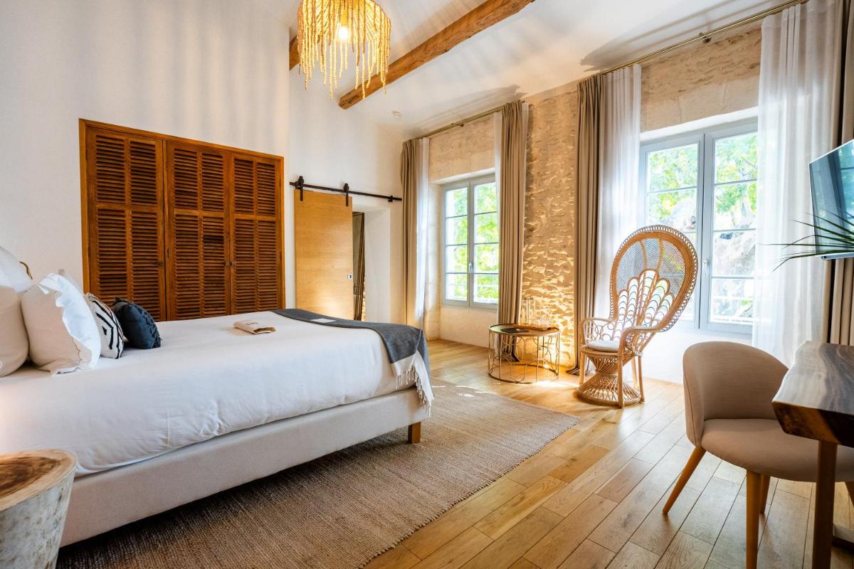 une chambre avec un lit, une chaise et des fenêtres dans l'établissement Hôtel Le Saint Remy & Spa, à Saint-Rémy-de-Provence
