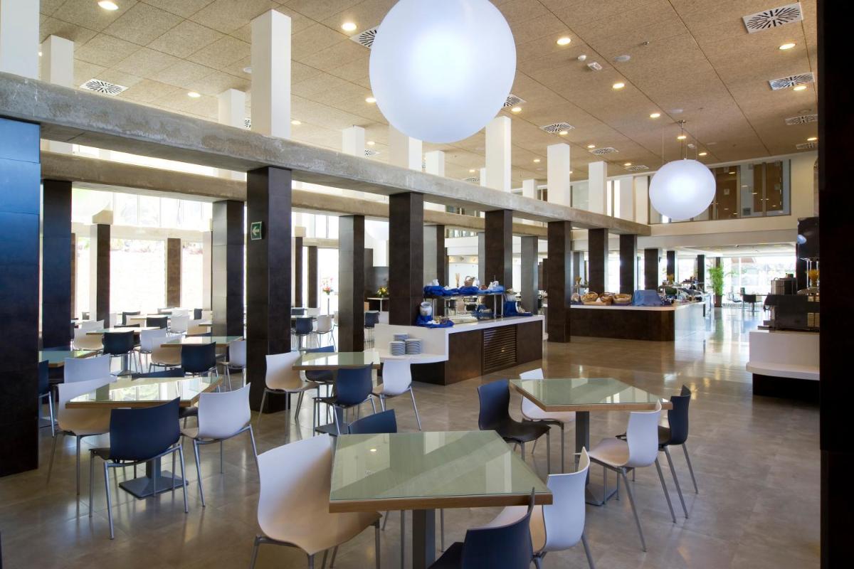 Un restaurante con mesas, sillas y luces. en R2 Romantic Fantasia Suites - Adults Only, en Tarajalejo