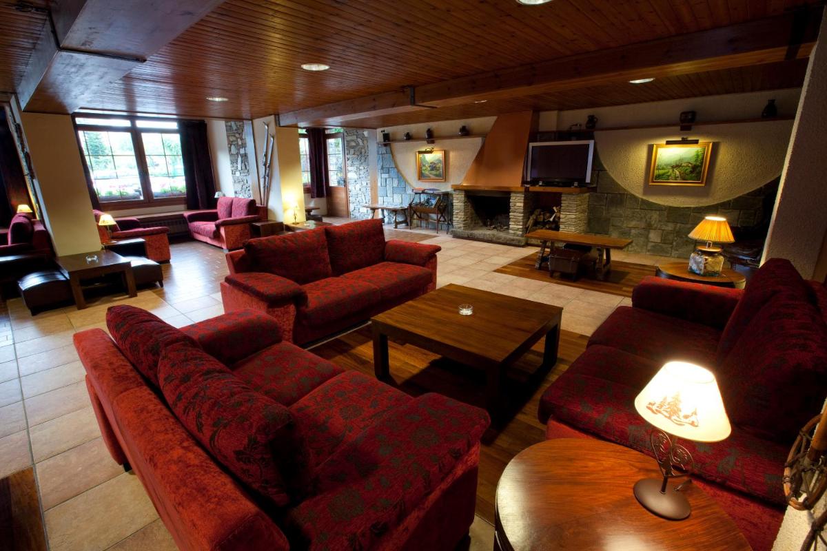 Una sala de estar con muebles rojos y chimenea. en Hotel La Morera, en Valencia de Aneu