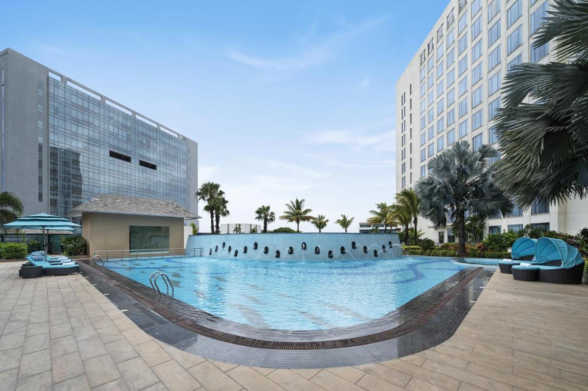 a large swimming pool with people standing in the water at Bengaluru Marriott Hotel Whitefield in Bengaluru