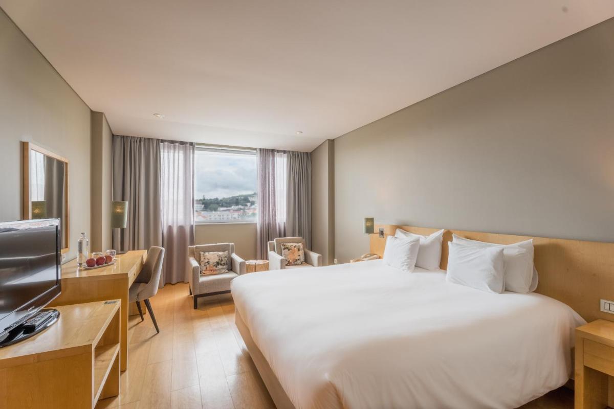 um quarto de hotel com uma cama grande e uma televisão em The Lince Azores em Ponta Delgada