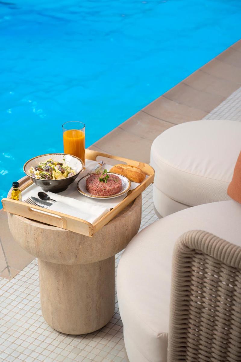 un plateau de nourriture sur une table à côté d'une piscine dans l'établissement Waldorf Astoria Versailles - Trianon Palace, à Versailles