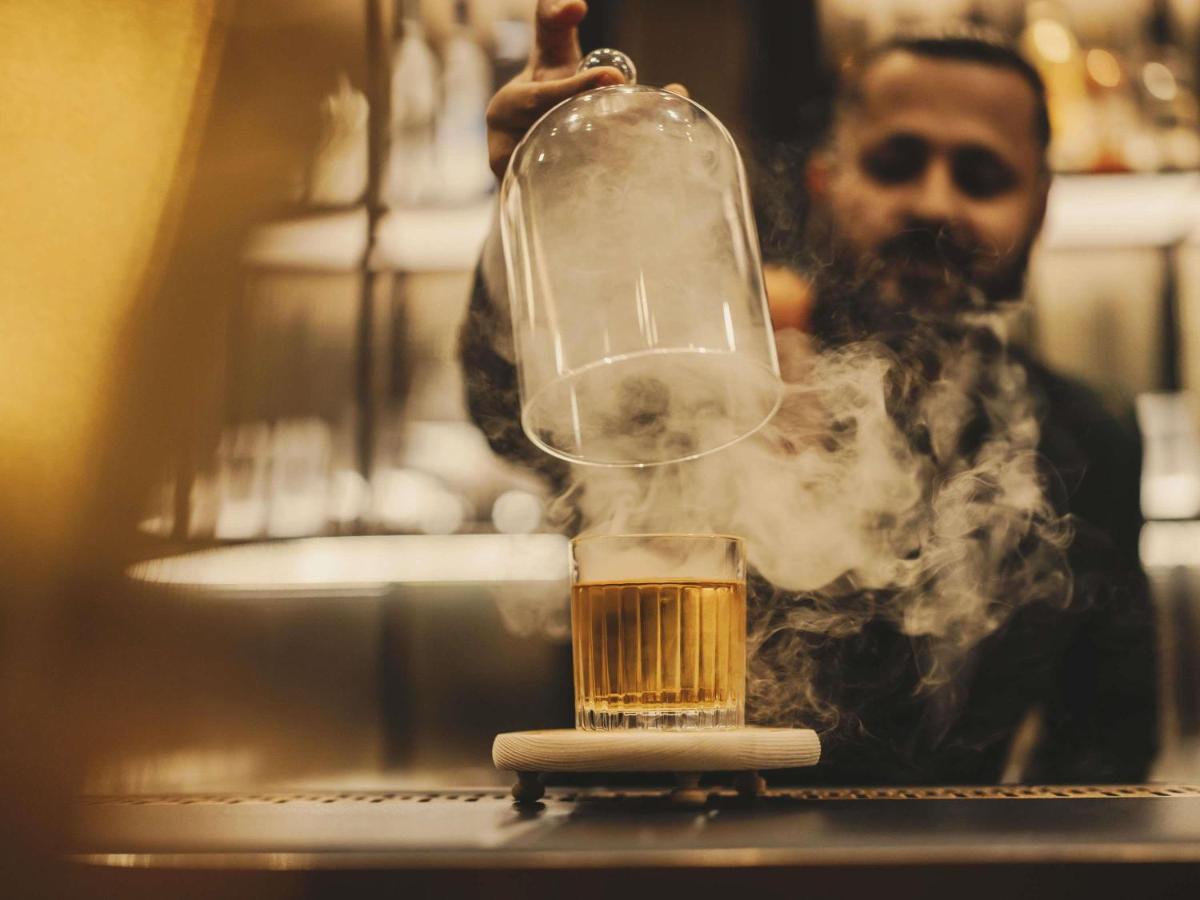 a man holding up a glass container with a drink at Fairmont Mumbai in Mumbai