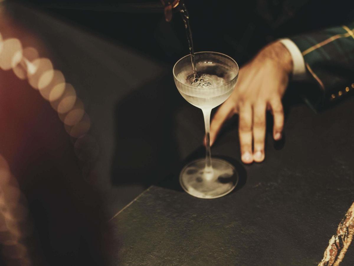 a person pours a drink into a martini glass at Fairmont Mumbai in Mumbai