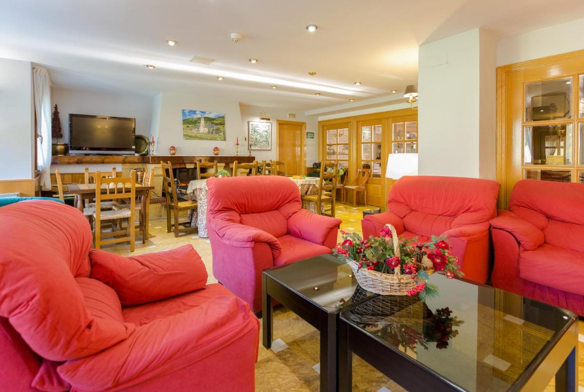 Una sala de estar con sillas rojas y una mesa. en Hotel Eth Solan & SPA, en Vielha
