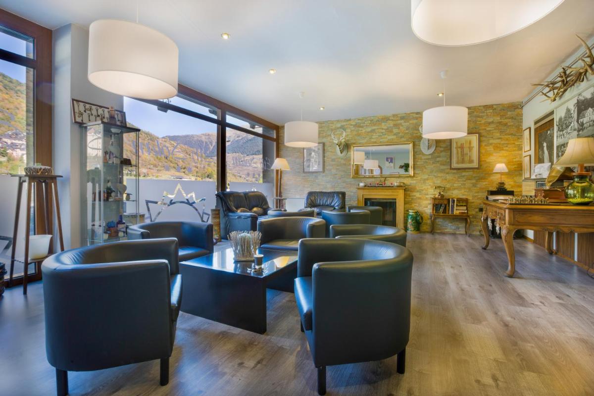 Una sala de estar con sillas, una mesa y un piano. en Hotel Eth Solan & SPA, en Vielha