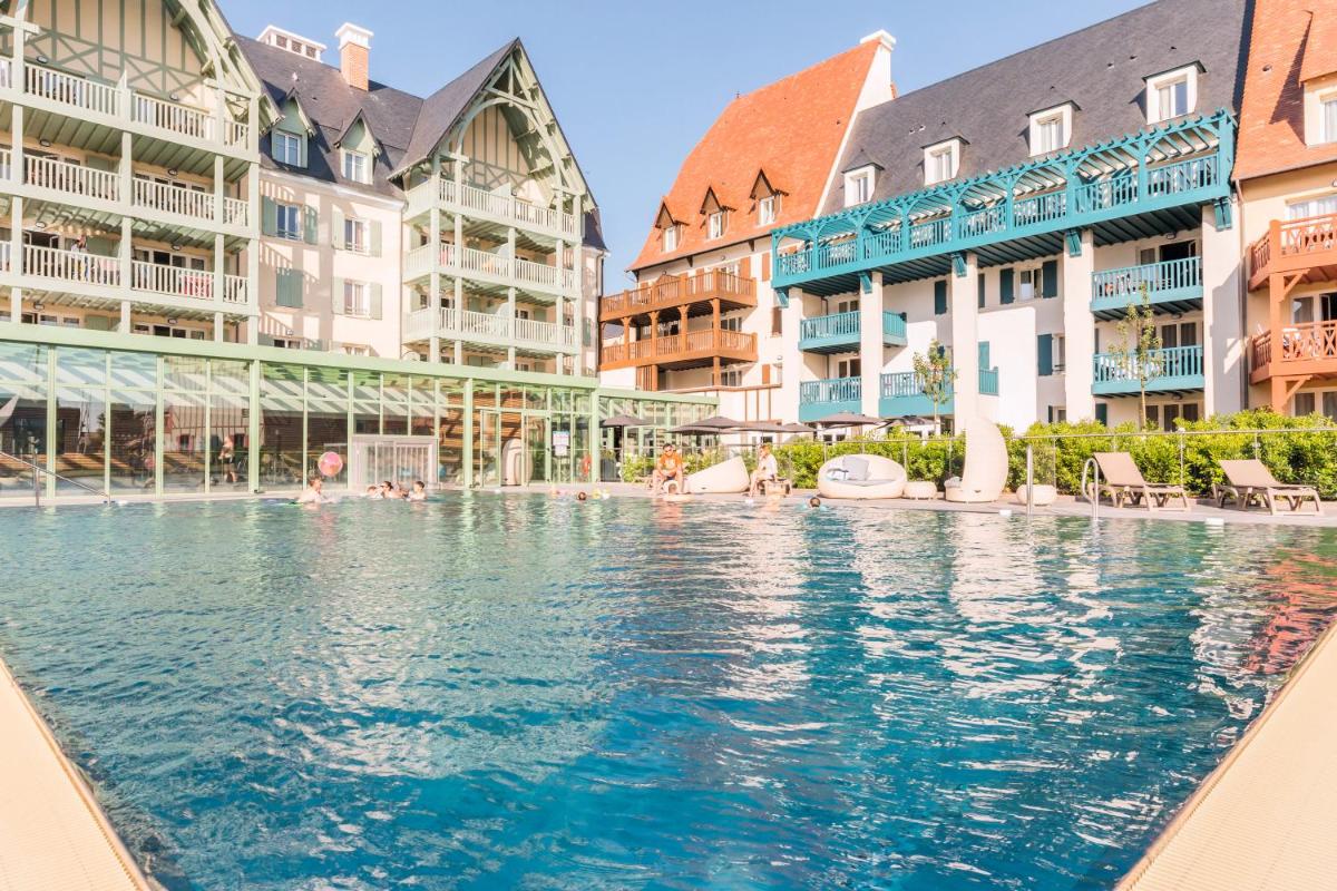 une piscine dans un complexe hôtelier avec des bâtiments dans l'établissement Résidence Pierre & Vacances Premium Presqu'Ile de la Touques, à Deauville