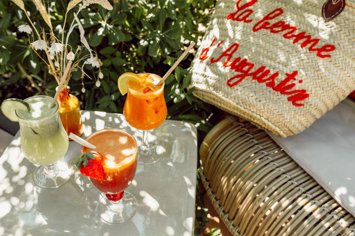 Deux cocktails sur une table en verre à côté d'un oreiller dans l'établissement La Ferme D'Augustin, à Saint-Tropez