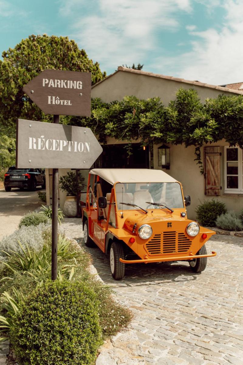 une voiture orange garée à côté d'un panneau de signalisation dans l'établissement La Ferme D'Augustin, à Saint-Tropez
