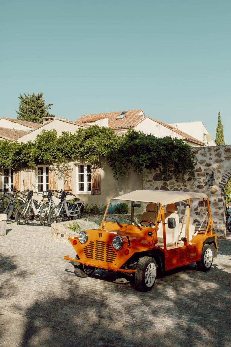 une voiturette de golf orange garée devant un bâtiment dans l'établissement La Ferme D'Augustin, à Saint-Tropez