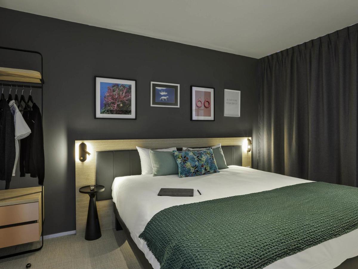 une chambre avec un grand lit recouvert d'une couverture verte dans l'établissement Aparthotel & Spa Adagio Vannes, à Vannes