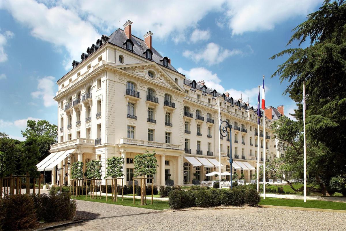 un bâtiment blanc avec un drapeau dessus dans l'établissement Waldorf Astoria Versailles - Trianon Palace, à Versailles