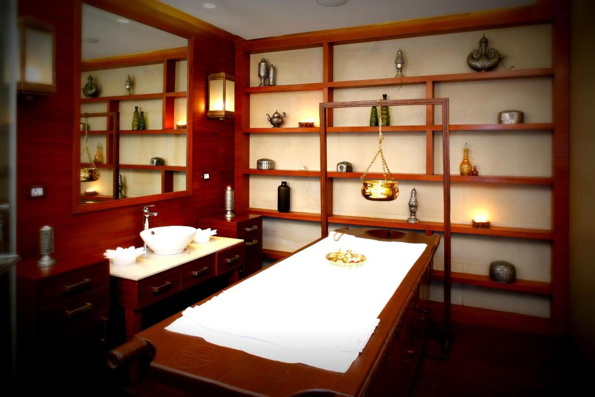 a bathroom with a sink and a counter and shelves at Jaypee Palace Hotel in Agra