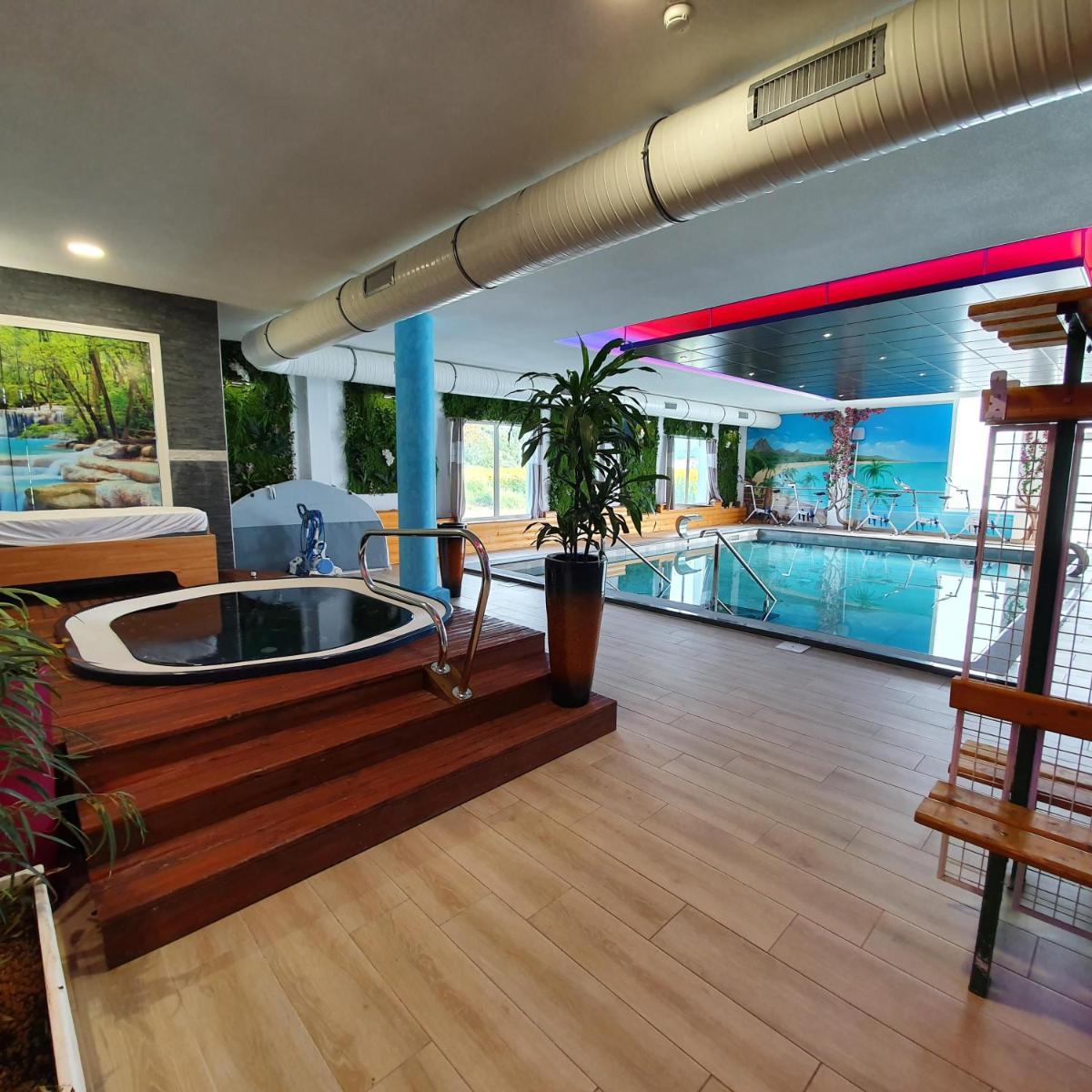 une grande chambre avec une baignoire et une piscine dans l'établissement Best Western Hotel & SPA Pau Lescar Aeroport, à Lescar