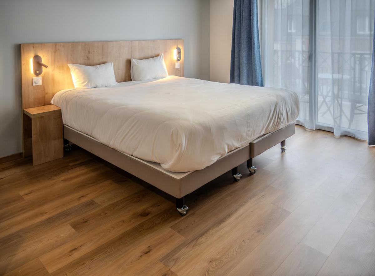 un grand lit dans une chambre avec un plancher en bois dans l'établissement Tulip Inn Honfleur Residence & Spa, à Honfleur 88 autres photos