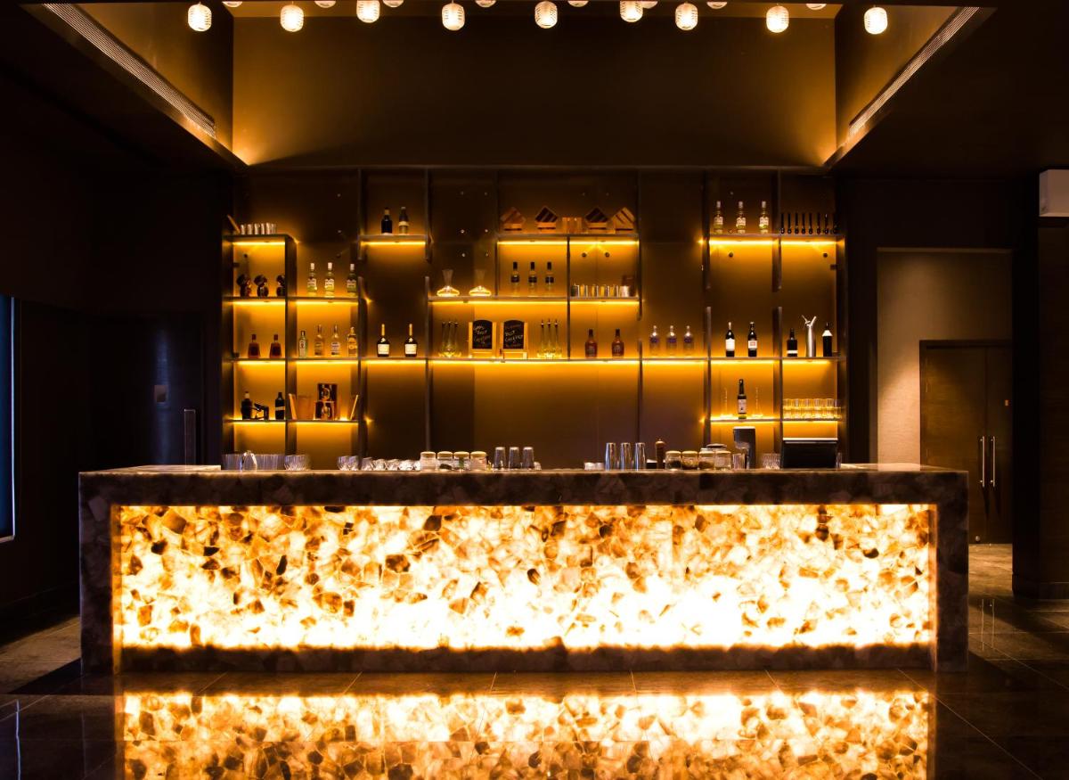 a bar in a room with lights on the wall at Feathers- A Radha Hotel, Chennai in Chennai
