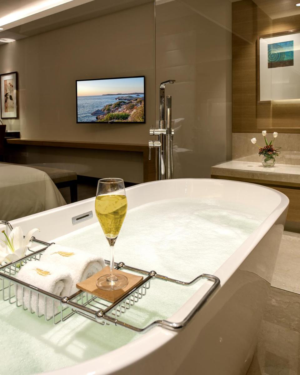 a bathtub with a glass of wine in a room at Feathers- A Radha Hotel, Chennai in Chennai