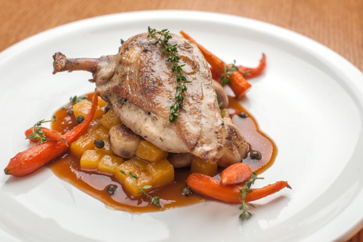 a white plate with a piece of meat and carrots at Feathers- A Radha Hotel, Chennai in Chennai