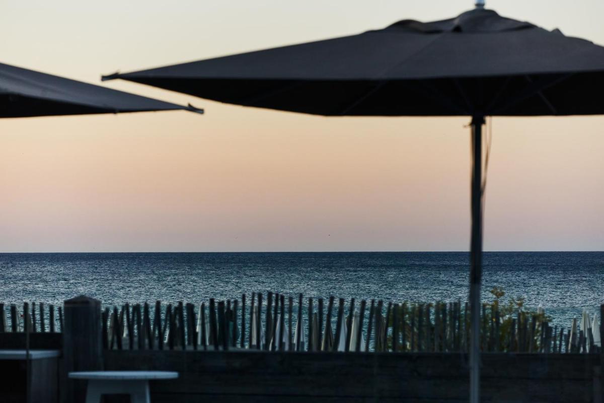 un parasol sur la plage, près d'une clôture dans l'établissement Hôtel Plage Palace & Spa, à Palavas-les-Flots 131 autres photos