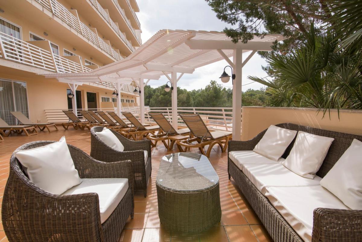un patio al aire libre con sillas de mimbre y una mesa en azuLine Hotel Bahamas y Bahamas II, en El Arenal