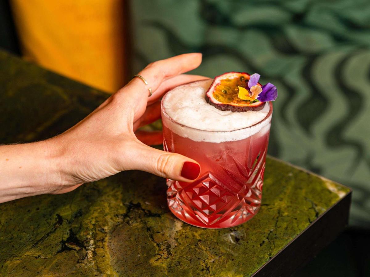 une main tenant un verre avec une fleur dessus dans l'établissement Pullman Paris Centre - Bercy, à Paris