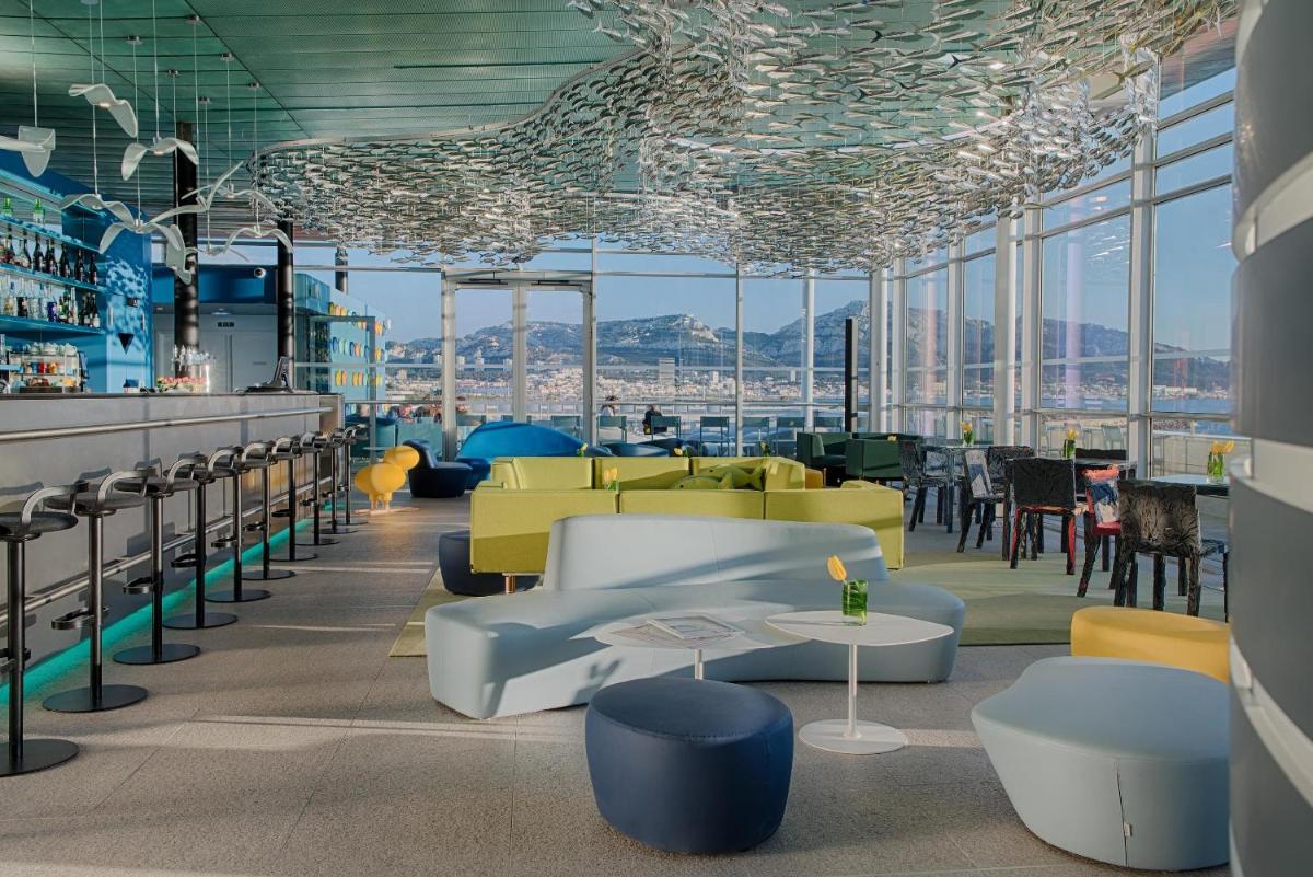 - un bar avec des chaises, des tables et des fenêtres dans l'établissement nhow Marseille, à Marseille