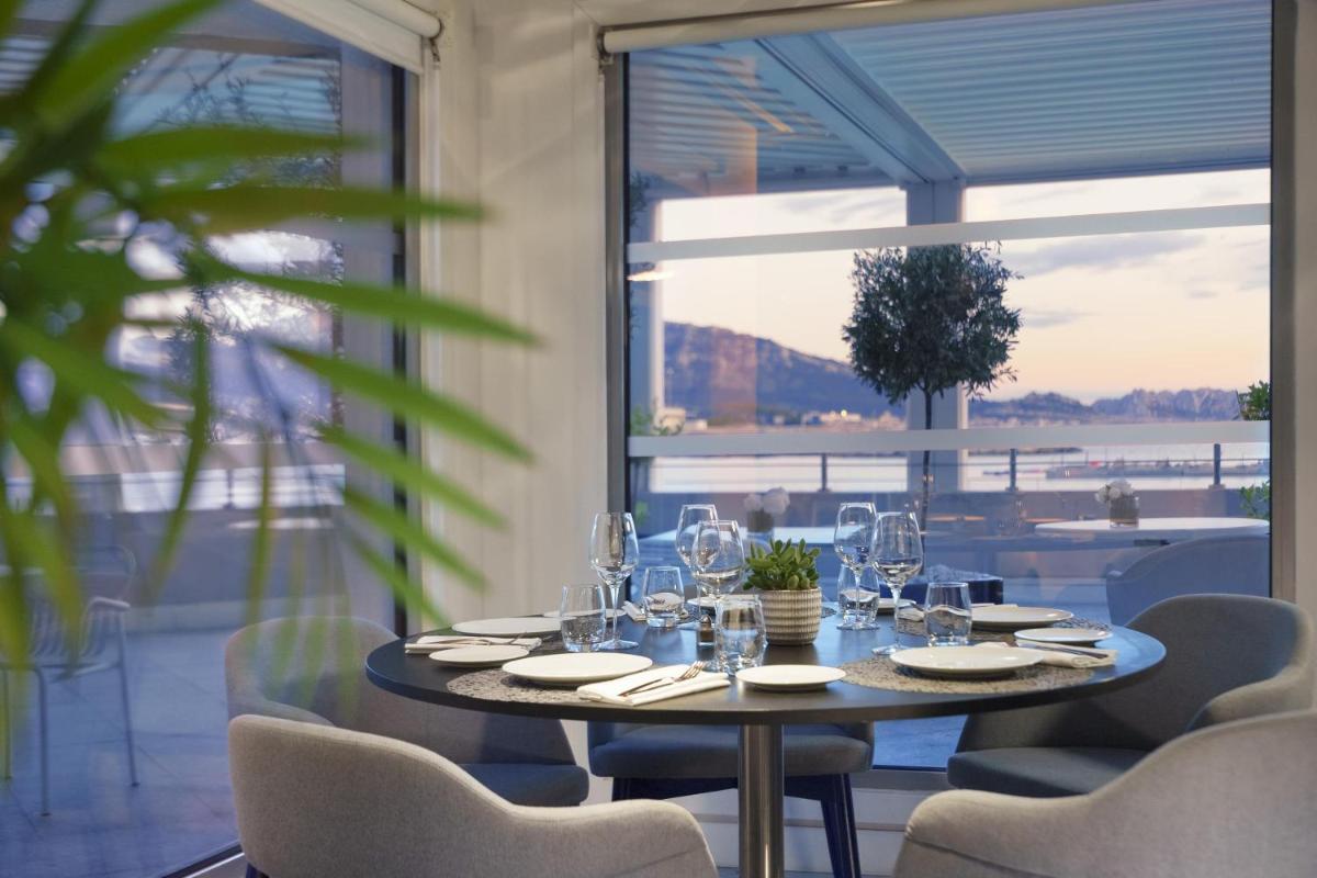une salle à manger avec une table et des chaises et une grande fenêtre dans l'établissement nhow Marseille, à Marseille