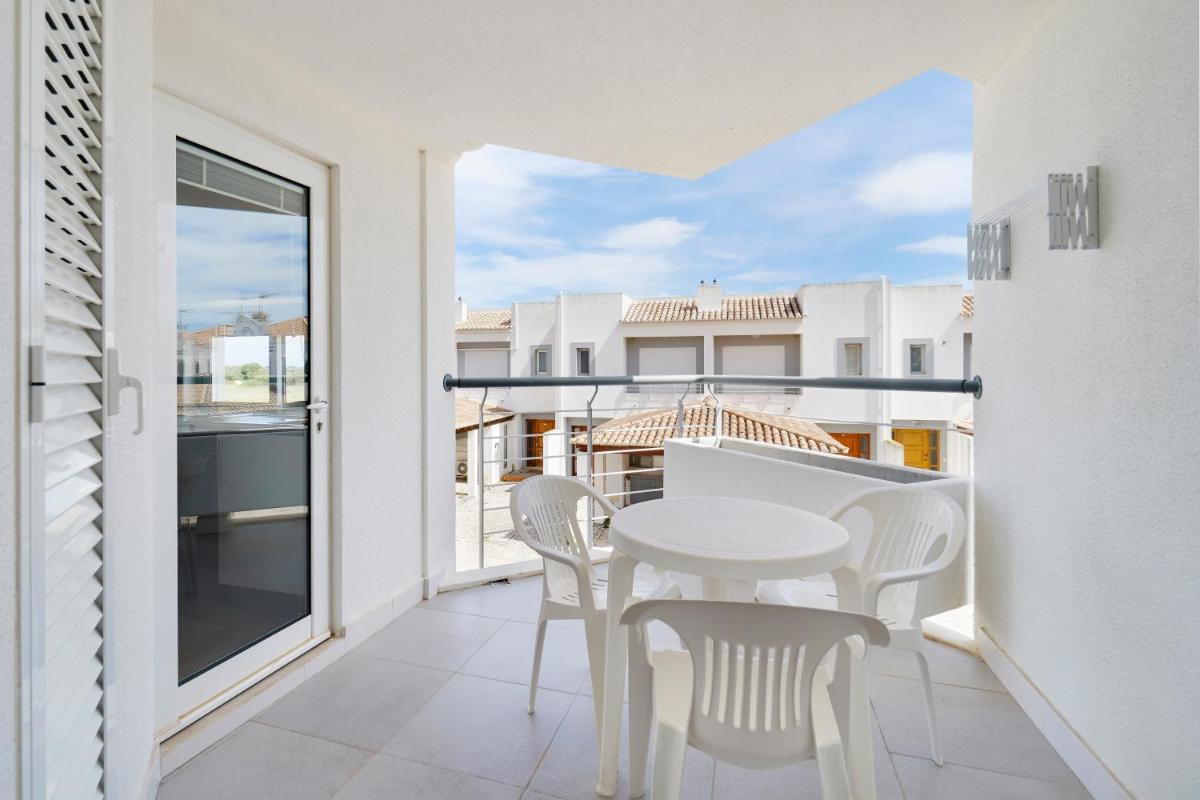 uma varanda branca com uma mesa e cadeiras brancas em Golden Club Cabanas em Cabanas de Tavira