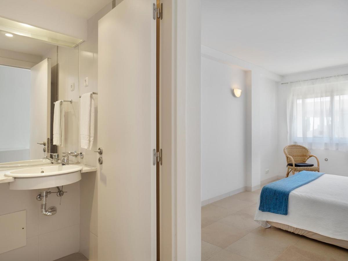 um quarto com uma cama, uma pia e um espelho em Golden Club Cabanas em Cabanas de Tavira