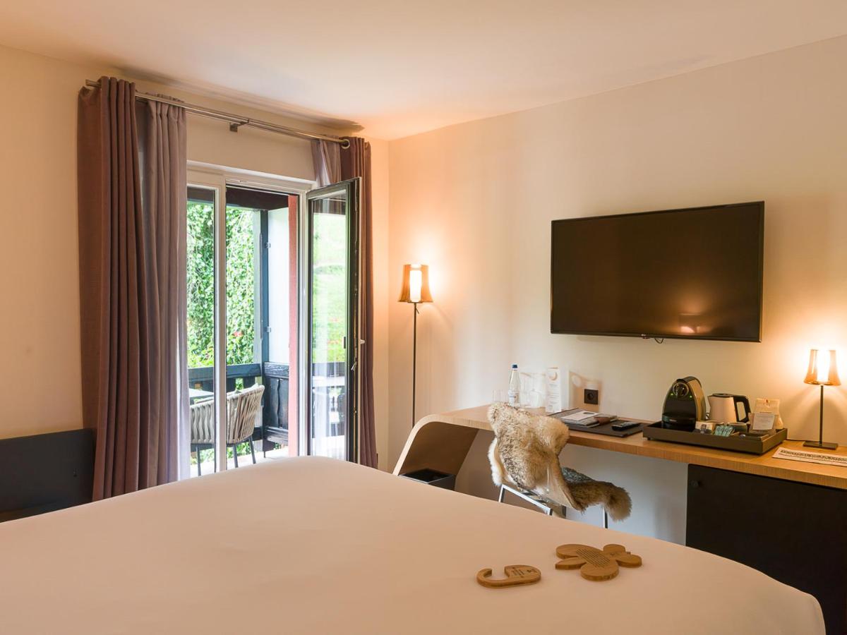 une chambre d'hôtel avec un lit, un bureau et une télévision dans l'établissement Relais et Châteaux Le Chambard, à Kaysersberg