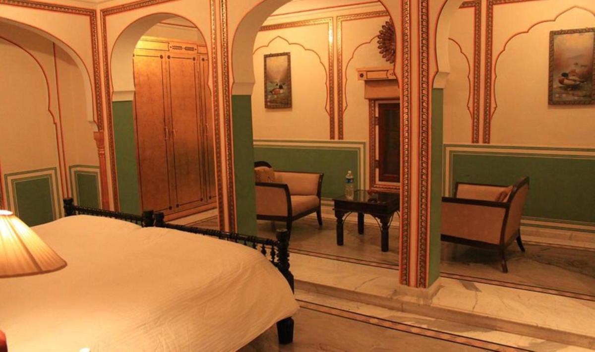 a bedroom with a bed and a mirror at The Raj Palace (Small Luxury Hotels of the World) in Jaipur