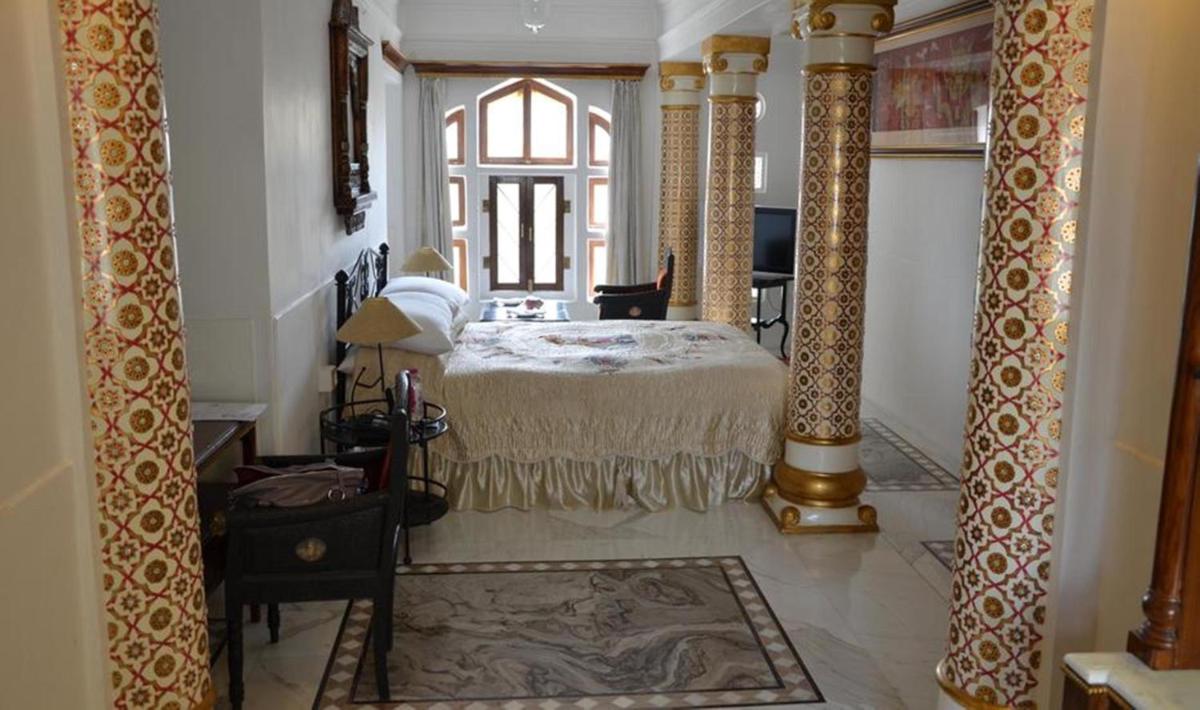 a bedroom with a bed and a large window at The Raj Palace (Small Luxury Hotels of the World) in Jaipur