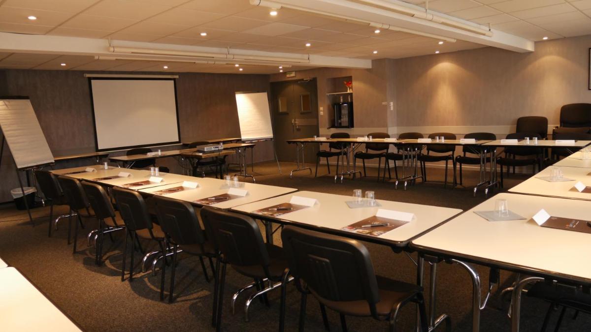 une salle de conférence avec des tables et des chaises et un tableau blanc dans l'établissement Hotel L'Hotan, à Portet-sur-Garonne