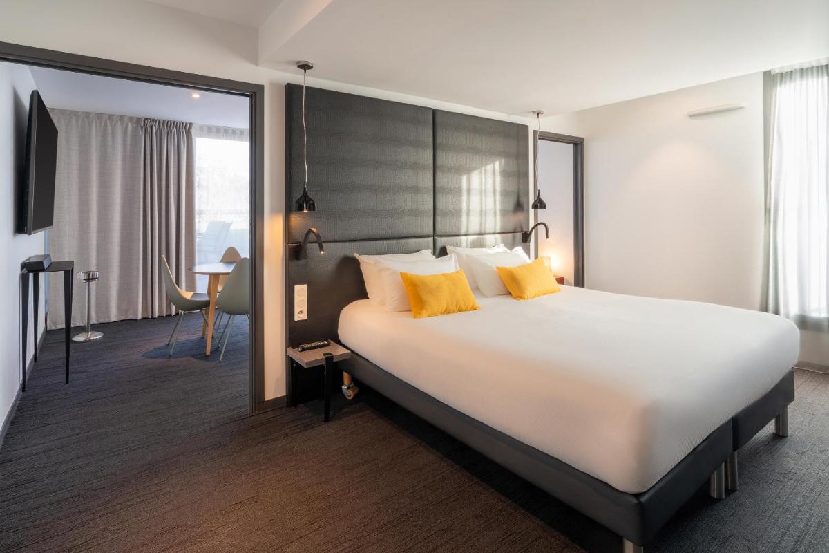 une chambre d'hôtel avec un grand lit aux oreillers jaunes dans l'établissement BW Plus Central Park Hotel & Spa, à La Rochelle