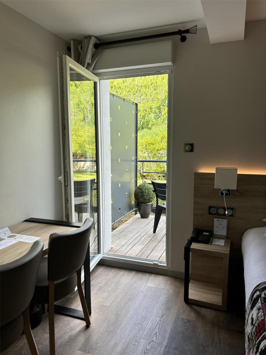 une chambre avec une porte donnant sur une terrasse avec une table et un lit dans l'établissement Best Western Plus Hotel & SPA Le Schoenenbourg, à Riquewihr