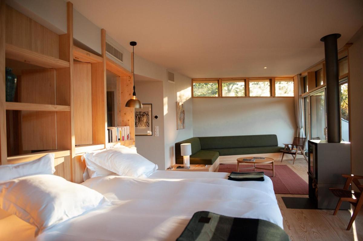 une chambre avec deux lits et un canapé vert dans l'établissement Les Échasses Golf & Surf Eco Lodge, à Saubion