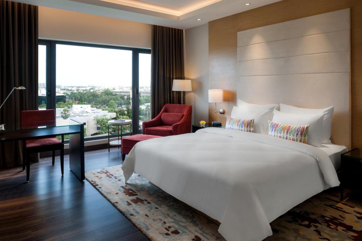 a bedroom with a large white bed and a desk at Feathers- A Radha Hotel, Chennai in Chennai