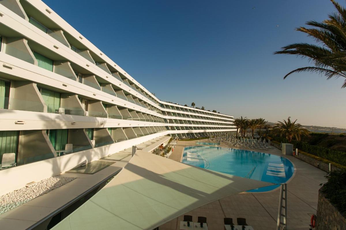 Un gran edificio con piscina y palmeras. en Santa Monica Suites Hotel, en Playa del Inglés