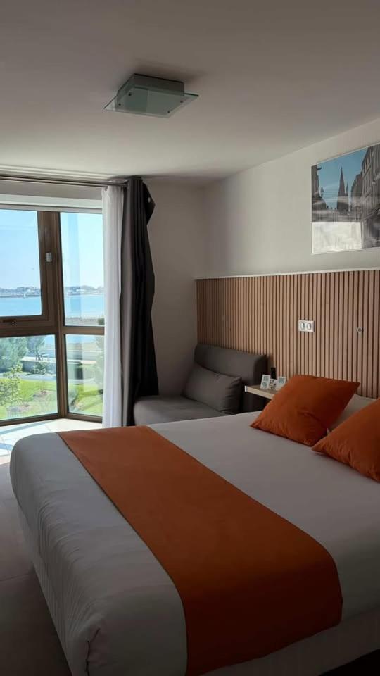 une chambre avec un grand lit et une fenêtre dans l'établissement Logis Hôtel Le Rochelois, à La Rochelle