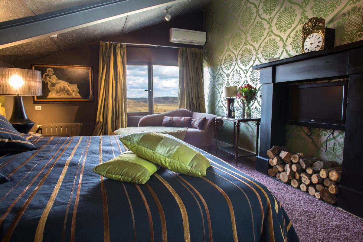 1 dormitorio con cama con almohadas verdes y chimenea en Hotel Cardamomo Sigüenza, en Carabias