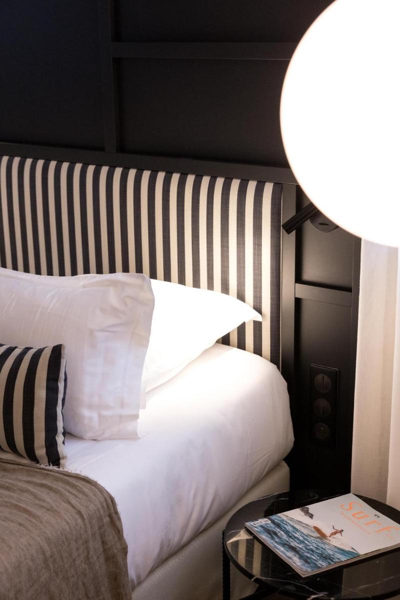 une chambre avec un lit blanc et une table avec une lampe dans l'établissement Le Celtique & Spa, à Carnac 115 autres photos