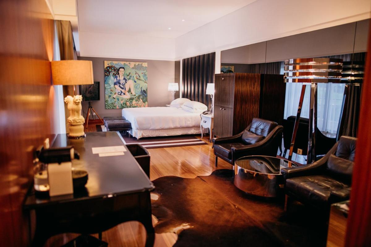 uma sala de estar com um quarto com cama e sofá em Convento do Espinheiro, Historic Hotel & Spa em Évora