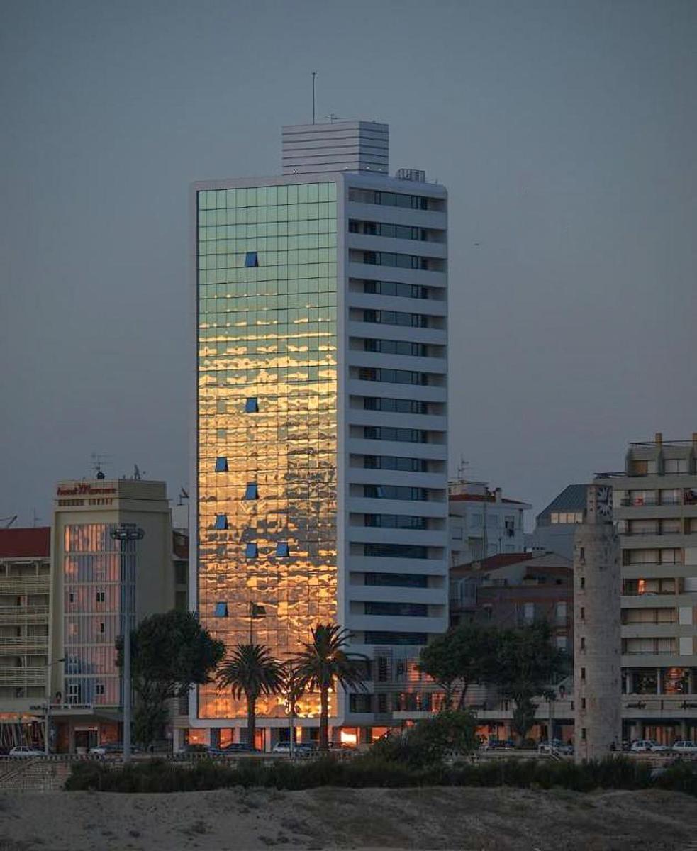 um prédio alto com suas luzes acesas em uma cidade em Sweet Atlantic Hotel & Spa na Figueira da Foz